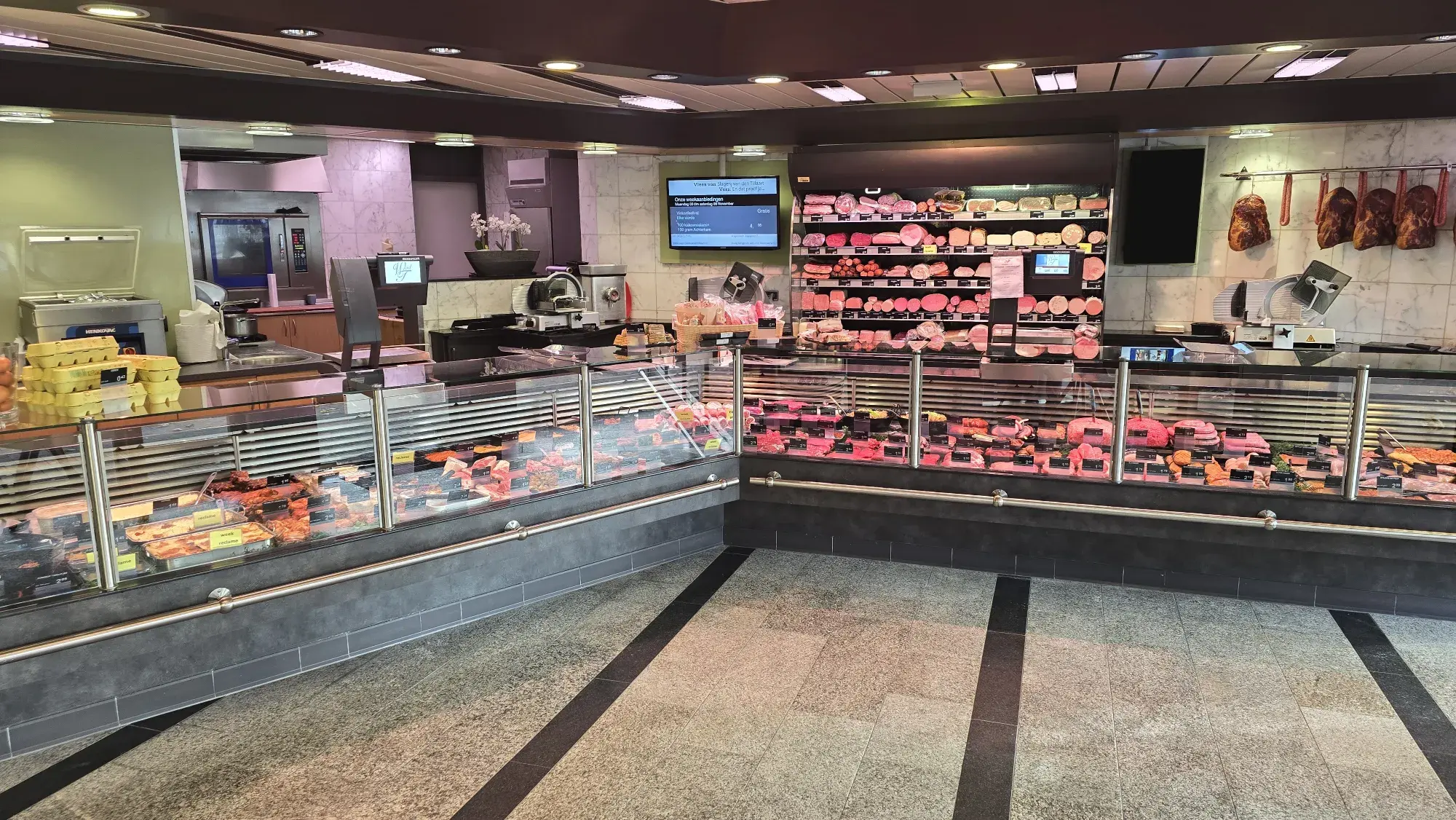 Binnenzicht van Slagerij Ophuis met de toonbank vol ambachtelijke vleeswaren en versproducten.